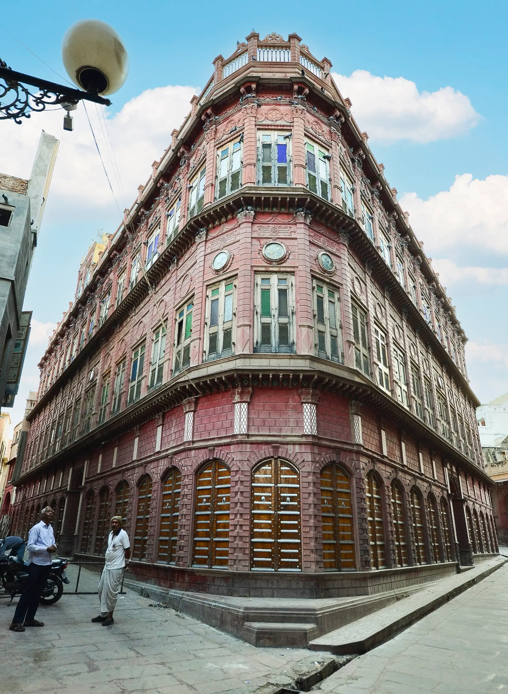 Corner of the Rampuria Haveli in Old Bikaner, with carved sandstone balconies and arched ground-floor windows rising above a narrow lane